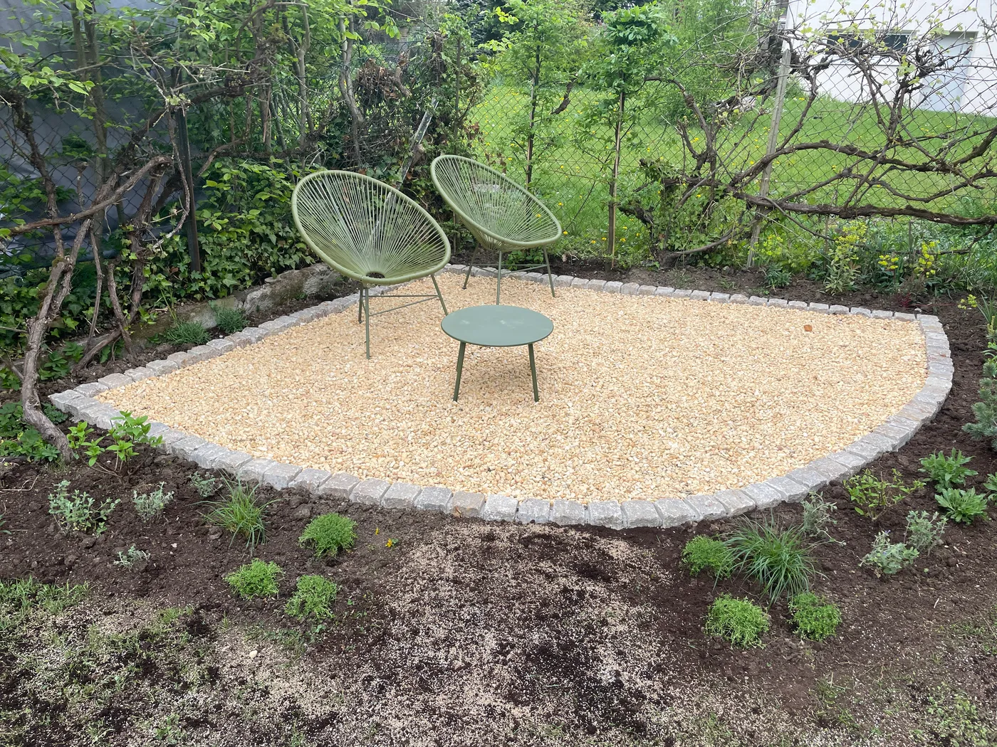 Neu angelegter Sitzplatz mit Kiesfläche und frischer Bepflanzung